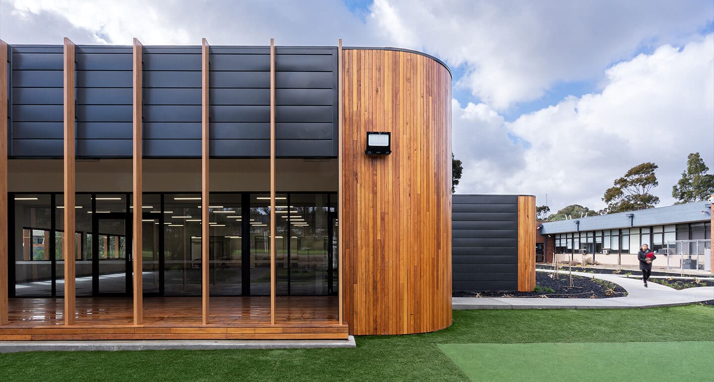 a building with a wood wall and a green lawn