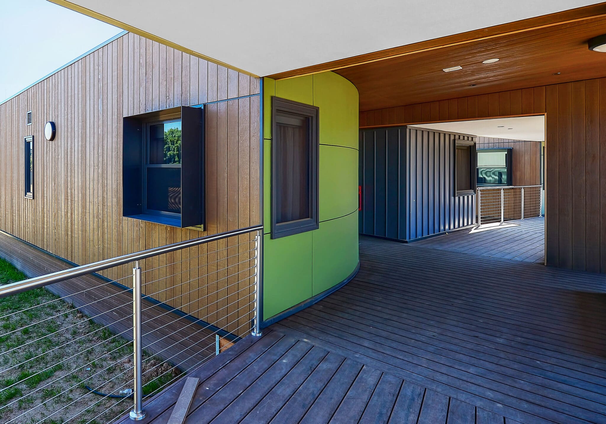 a deck with a green wall and a metal railing